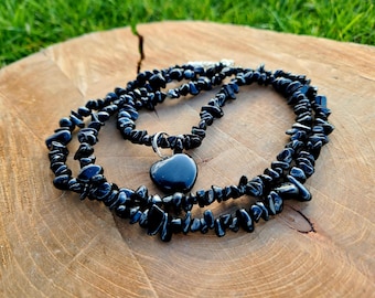 Puede incluir: Collar de chips de obsidiana negra con un colgante en forma de corazón. El collar está hecho de pequeñas piezas irregulares de obsidiana, que están enhebradas en una cadena de plata. El colgante también está hecho de obsidiana y tiene forma de corazón.