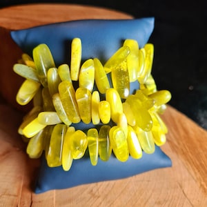 Könnte beinhalten: Ein Armband aus gelben Edelsteinen mit mehreren Reihen kleiner, unregelmäßig geformter Steine.