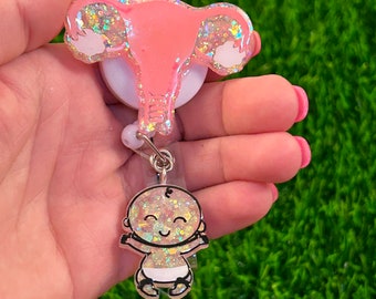 May include: A pink glitter uterus charm with a baby charm attached to a retractable badge reel.