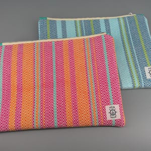 May include: Two colorful zippered pouches with a chevron pattern. One pouch is pink, orange, and teal, and the other is blue, green, and yellow. Each pouch has a white tag with a nautical emblem and the text "HEM HELM".