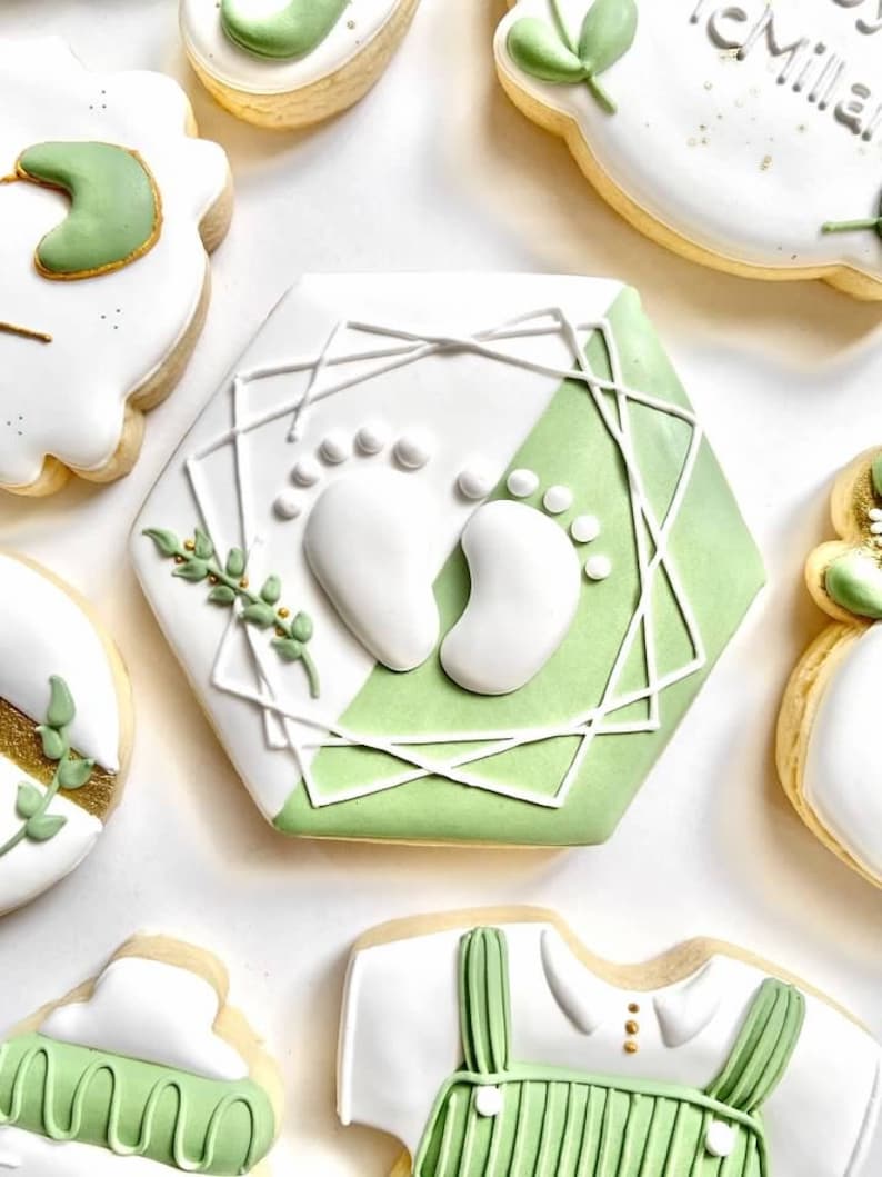 Peut inclure: Un ensemble de six biscuits d&eacute;cor&eacute;s en sucre avec un th&egrave;me vert et blanc. Les biscuits repr&eacute;sentent un body de b&eacute;b&eacute;, des empreintes de pieds et des feuilles.