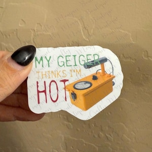 May include: White sticker with a yellow and black Geiger counter and the text "My Geiger thinks I'm hot".