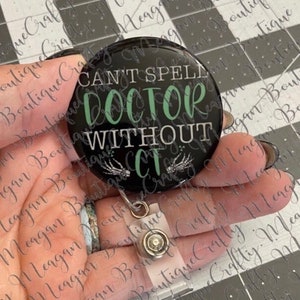 May include: A black and green round badge with a white background and the text "Can't Spell Doctor Without CT" in white and green lettering. The badge is attached to a clear plastic retractable badge holder.