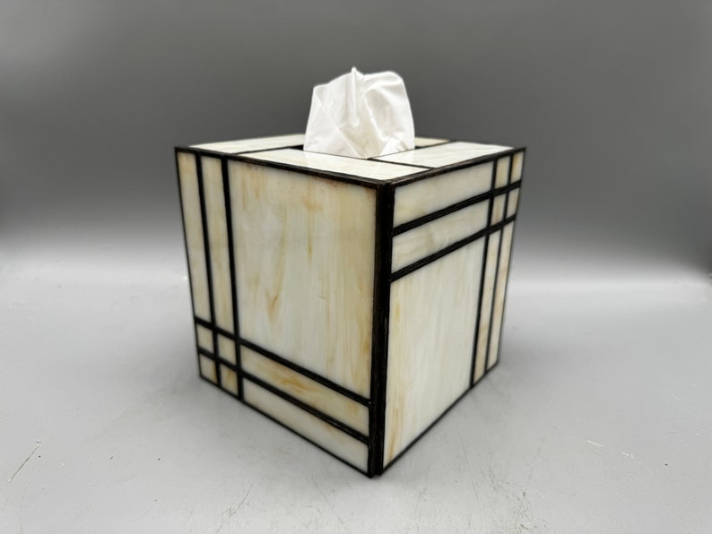 May include: A white tissue box cover with black geometric lines. The cover is made of stained glass and has a modern design.