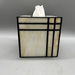 May include: A white tissue box cover with a black stained glass design. The design features geometric shapes and lines.