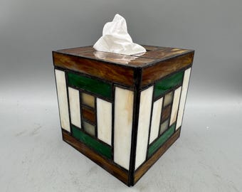 May include: A square tissue box cover made of stained glass with a geometric pattern of green, brown, and white glass pieces.
