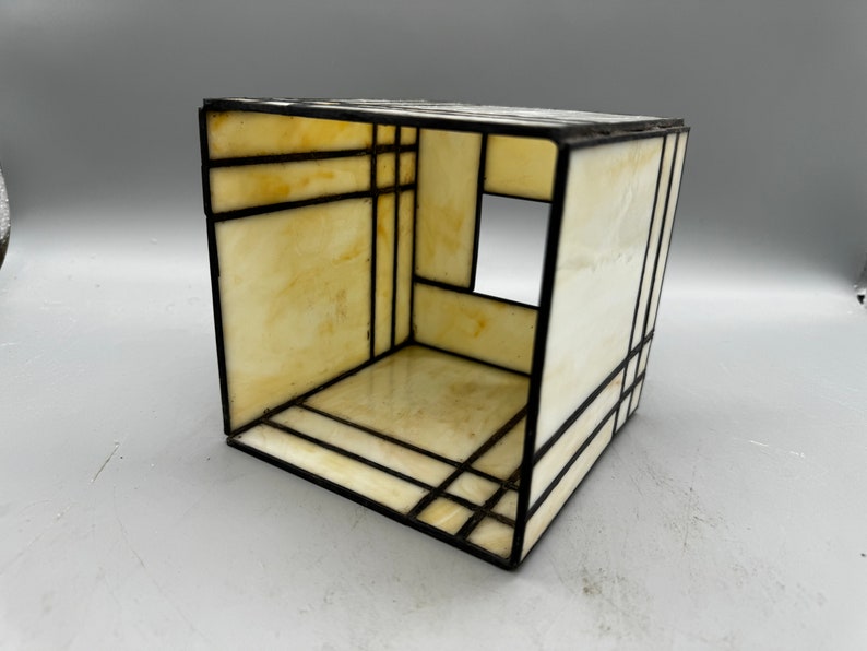 May include: A small, cube-shaped stained glass lampshade with a white and black geometric design. The lampshade is made of clear glass with black lines and a white interior.