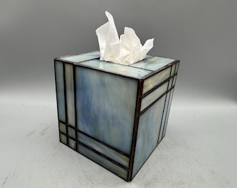 Op de afbeelding: Een vierkante tissuebox met een glas-in-lood ontwerp. De doos heeft een blauw-wit gemarmerd patroon met donkerbruine metalen omlijsting. Witte tissues zijn zichtbaar aan de bovenkant.