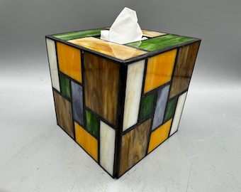 Könnte beinhalten: Ein quadratischer Taschentuchbox-Bezug aus Buntglas mit geometrischen Mustern in Braun-, Gelb-, Grün- und Weißtönen.