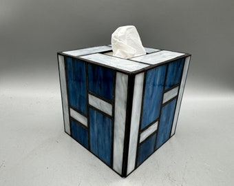 May include: A blue and white stained glass tissue box cover. The box is square and has a geometric pattern.
