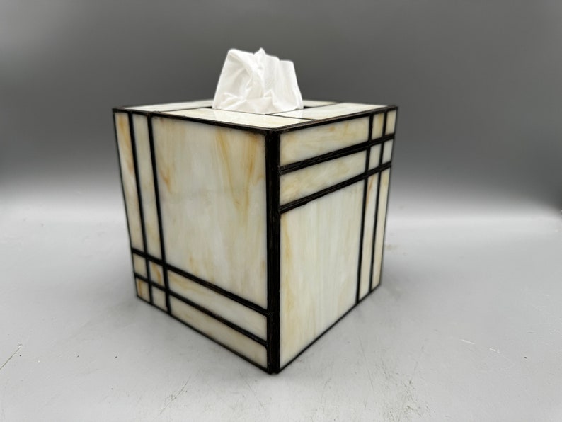 May include: A white and cream stained glass tissue box cover with black geometric lines.