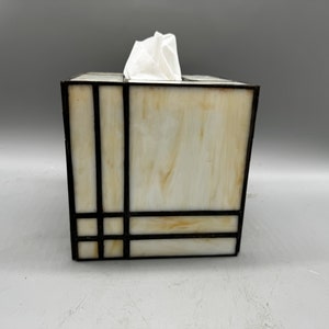 May include: A white tissue box cover with a geometric design in black stained glass.