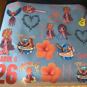 May include: A light blue sheet featuring various stickers including a large orange hibiscus flower, a parrot, a guitar, barbed wire hearts, and cartoon figures. Text includes KAROL G, TROPI TOUR, and the number 26 in large orange font.