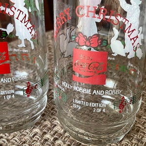 May include: Clear glass Coca-Cola Christmas glasses. Each glass features a red Coca-Cola logo, the words "Merry Christmas", and "Holly Hobbie and Robby". Limited edition, 1979.