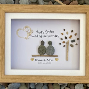 May include: A framed pebble art piece with a golden heart and a tree made of pebbles. The text reads "Happy Golden Wedding Anniversary Doreen & Adrian 27th May 1972".