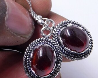 Puede incluir: Un par de pendientes de plata con cabujones de piedras preciosas rojas engastados en marcos de plata ornamentados. Los pendientes tienen un cierre de gancho simple.