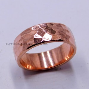May include: A hammered copper ring with a wide band. The ring has a textured surface and a polished finish.