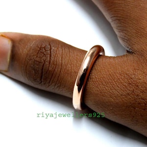 Könnte beinhalten: Ein schlichter Roségold-Ring, der an einem Finger getragen wird.