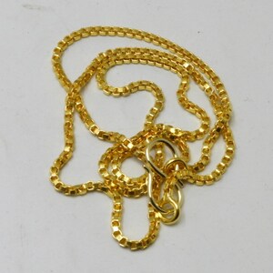 May include: A gold chain necklace with a box chain design. The chain is about 20 inches long and has a lobster clasp.