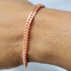 Peut inclure: Un bracelet en cuivre avec un motif tiss&eacute;. Le bracelet est port&eacute; au poignet.