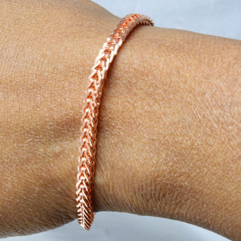 Peut inclure: Un bracelet en cuivre avec un motif tiss&eacute;. Le bracelet est port&eacute; au poignet.