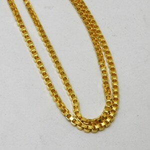 May include: A gold chain necklace with a box chain design. The chain is made of small, square links.