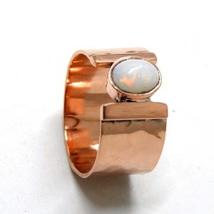Op de afbeelding: Een koperen ring met een witte opaal-edelsteen gezet in een gehammerde band.