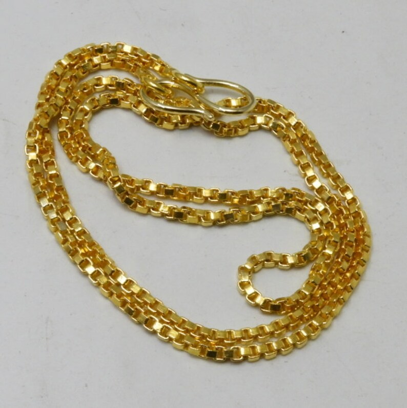 May include: A gold chain necklace with a box chain design. The chain is approximately 20 inches long and has a lobster clasp closure.