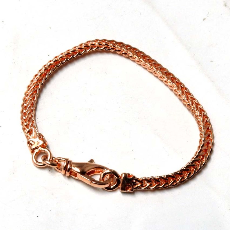 Peut inclure: Un bracelet en cha&icirc;ne or rose avec une fermeture &agrave; fermoir. La cha&icirc;ne est de conception tress&eacute;e.