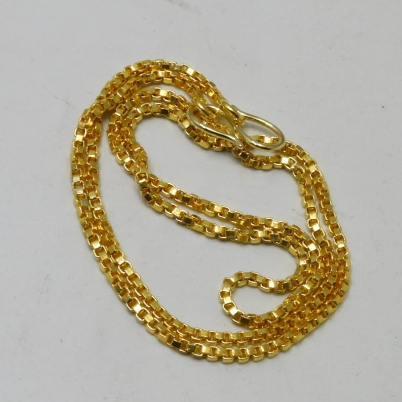 May include: A gold chain necklace with a box chain design. The chain is about 20 inches long and has a lobster clasp.