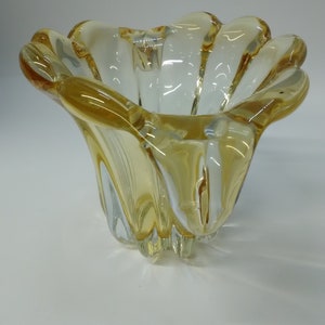 May include: A clear glass bowl with a yellow tint and a wavy, flower-like design.