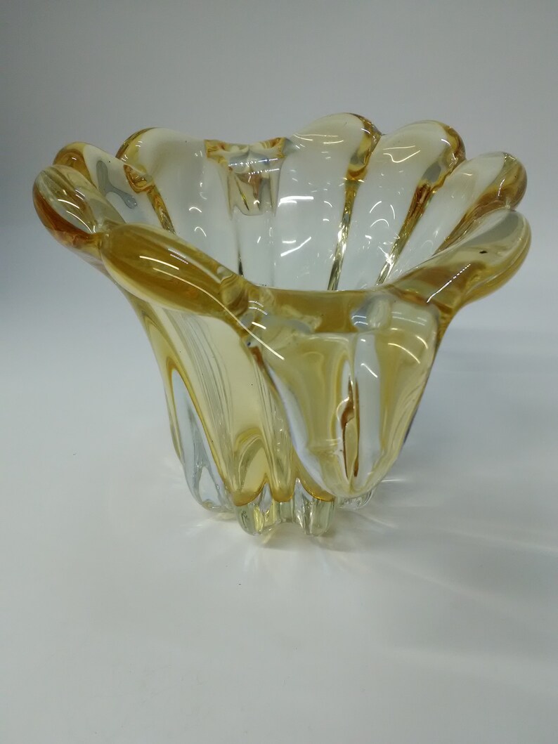 May include: A clear glass bowl with a yellow tint and a wavy, flower-like design.