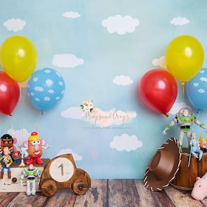 Op de afbeelding: Toy Story-thema verjaardagsachtergrond met een blauwe lucht, witte wolken en ballonnen. De achtergrond heeft een houten speelgoedauto met het nummer 1 erop, een houten vat en een verscheidenheid aan Toy Story-personages, waaronder Woody, Buzz Lightyear en Mr. en Mrs. Potato Head.