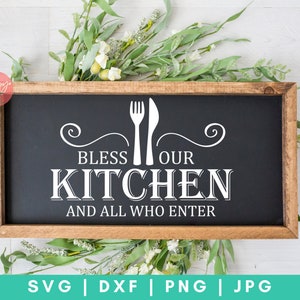 May include: A black sign with a wooden frame, featuring white text that reads "Bless Our Kitchen and All Who Enter". The text is accompanied by a fork and knife graphic.
