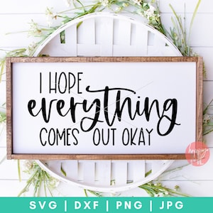 Peut inclure: Une pancarte en bois blanc avec un cadre brun, sur laquelle est inscrit le texte "J'espère que tout ira bien" en lettres cursives noires. La pancarte est entourée de verdure et de fleurs blanches.