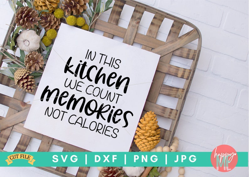 May include: A white sign with black text that reads "In this kitchen we count memories not calories". The sign is sitting on a wooden crate with fall-themed decorations.