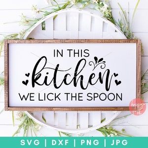 May include: A white wooden sign with the text "IN THIS kitchen WE LICK THE SPOON" in black lettering. The sign is sitting on a white wicker basket.