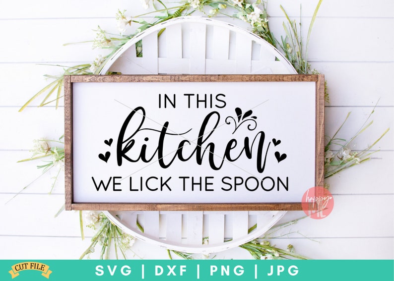 May include: A white wooden sign with the text "IN THIS kitchen WE LICK THE SPOON" in black lettering. The sign is sitting on a white wicker basket.