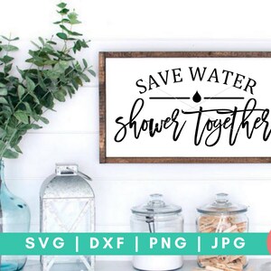 K&ouml;nnte beinhalten: Ein braunes Holzschild mit wei&szlig;em Text, der "Save Water Shower Together" lautet. Das Schild hat ein schwarzes Wassertropfen-Symbol &uuml;ber dem Wort "Together".