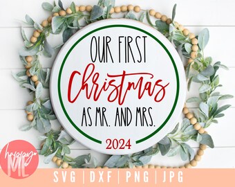 May include: White round sign with green and black lettering that reads "Our First Christmas as Mr. and Mrs. 2024". The sign is surrounded by a garland of green leaves and brown beads.