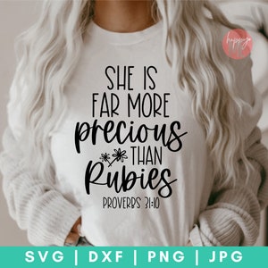 May include: A white t-shirt with black text that reads "She is far more precious than rubies Proverbs 31:10".