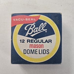 May include: A blue and yellow box with the text "VACU-SEAL Ball" in red and white. The box contains 12 regular mason dome lids.