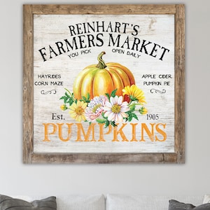 May include: A vintage-style sign for Reinhardt's Farmers Market, featuring a large orange pumpkin with white flowers, and the text "You Pick", "Open Daily", "Hayrides", "Corn Maze", "Apple Cider", "Pumpkin Pie", "Est. 1905", and "Pumpkins".