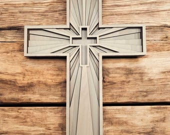 May include: A wooden cross with a sunburst design. The cross is made of light wood and has a simple, elegant design.