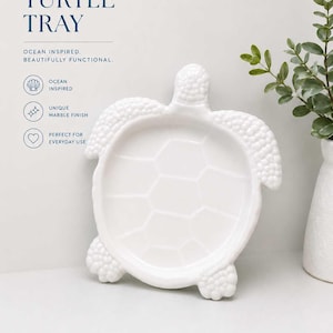 May include: A white ceramic turtle-shaped tray with a textured head and flippers, featuring a smooth, shallow basin with a hexagonal shell pattern. The text reads: TURTLE TRAY, OCEAN INSPIRED. BEAUTIFULLY FUNCTIONAL. OCEAN INSPIRED, UNIQUE MARBLE FINISH, PERFECT FOR EVERYDAY USE.