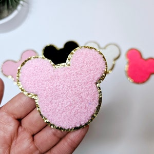 May include: Pink fuzzy Mickey Mouse head with a gold glitter outline.