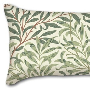 May include: A long rectangular cushion with a cream background and a repeating pattern of green and brown leaves.
