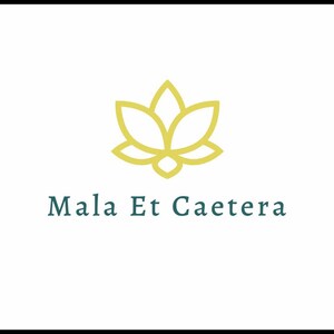 以下が含まれることがあります： 水色の文字「Mala Et Caetera」の上に、金の蓮の花のデザインが施されたロゴ。ロゴは黒い縁取りのある白い背景に配置されています。
