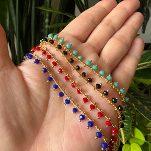 Peut inclure: Cinq cha&icirc;nes dor&eacute;es avec des perles pendantes turquoise, noires, rouges et bleues.
