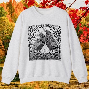 May include: A gray sweatshirt with a black and white illustration of two crows facing each other in a forest setting.